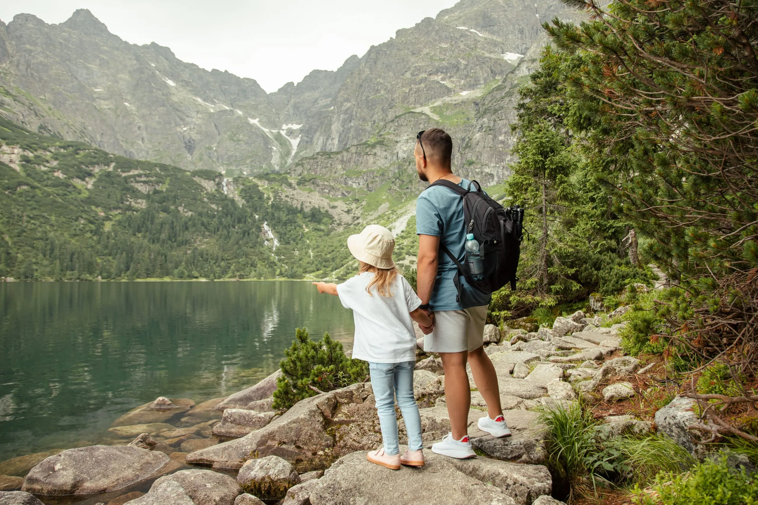 Mies ja lapsi turisteina vuoristossa Morskie Oko -järvellä Zakopanen lähellä, Tatra-vuoristossa, Puolassa. Perhematkakonsepti.